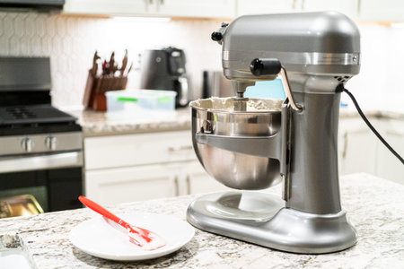 Stand mixer whips up creamy buttercream frosting to perfection, ready for dessert decorating.