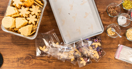 Carefully packaging Christmas cutout cookies, half-dipped in chocolate and presented in clear...