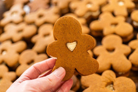 Making gingerbread man cookie sandwiches filled with eggnog buttercream, arrayed on a rustic wooden...