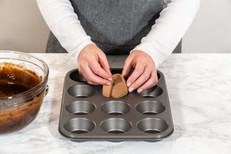 Getting ready to bake delicious chocolate cupcakes, we carefully line the cupcake pan with paper...