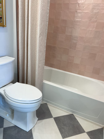 This inviting bathroom space features a classic white bathtub with a patterned shower curtain, soft...