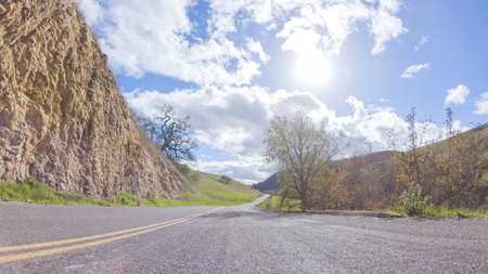 Vehicle is cruising along the Cuyama Highway under the bright sun. The surrounding landscape is illuminated by the radiant sunshine, creating a picturesque and inviting scene as the car travels through this captivating area.の写真素材