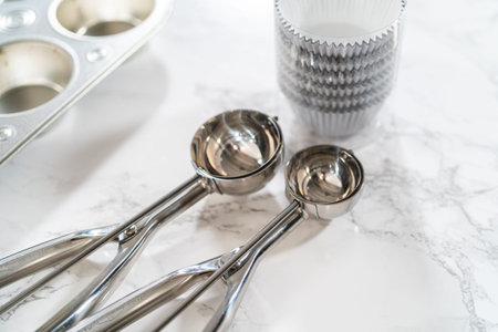 Cupcake foil liners are being meticulously filled with both chocolate and vanilla batter, setting...
