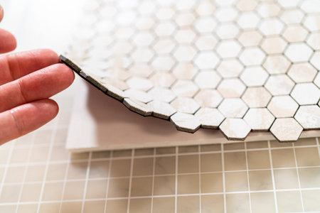 In the process of mounting peel and stick mosaic tiles onto a foam board, perfect for enhancing a...