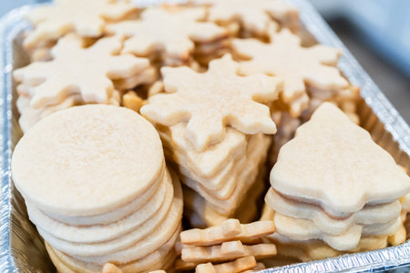 Carefully stacking the beautifully crafted snowflake-shaped sugar cookies into a foil pan, ready for...