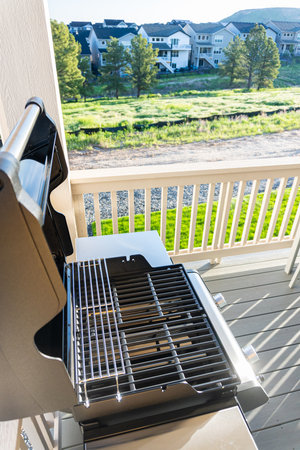 Sleek, open-lid, two-burner grill stands ready for use, conveniently positioned on the balcony of a suburban home, promising a delightful alfresco cooking experience.の写真素材