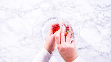 Flat lay. Ripe strawberries are submerged in water within a large glass mixing bowl, a step in washing the fruit to ensure cleanliness and longevity before storage or consumption.の写真素材