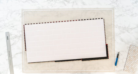 In the process of mounting peel and stick mosaic tiles onto a foam board, perfect for enhancing a...