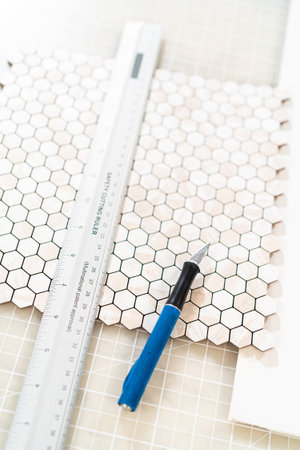 In the process of mounting peel and stick mosaic tiles onto a foam board, perfect for enhancing a...