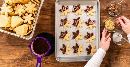 Preparing star-shaped cookies, half-dipped in chocolate, accented with peppermint chocolate chips...