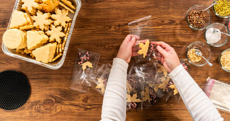 Carefully packaging Christmas cutout cookies, half-dipped in chocolate and presented in clear...