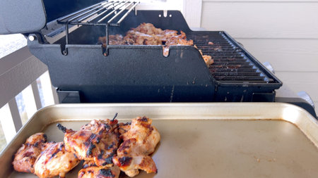 A close-up image capturing the process of grilling marinated chicken pieces, with a person expertly...