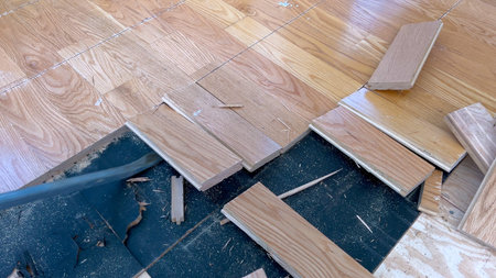 A scattered array of hardwood planks lies on a partially completed floor, highlighting the ongoing...