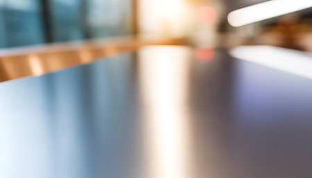 Capturing an extreme close-up of a modern cafÃ© table, this image highlights the minimalist aesthetic and reflective surface of the table during a brightly lit afternoon. The soft, even ambient lighting enhances the contemporary feel, with a subtly blurred cafÃ© interior in the background providing atmospheric depth.の素材