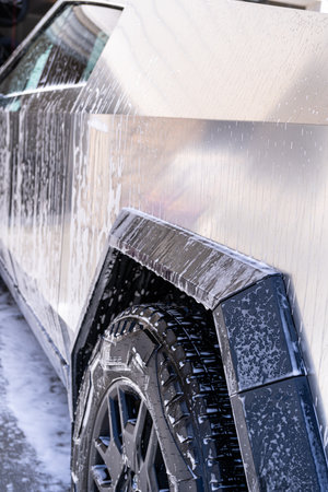 Denver, Colorado, USA-May 5, 2024-This image features a close-up view of the Tesla Cybertruck wheel and angular body design covered in soap and water during a thorough car wash, highlighting the unique textures and robust details of the electric truck.のeditorial素材