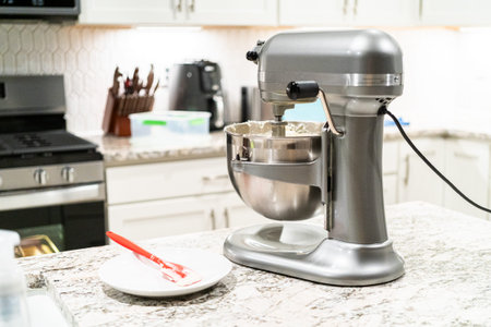 Stand mixer whips up creamy buttercream frosting to perfection, ready for dessert decorating.