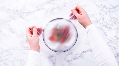 Flat lay. Strawberries, freshly washed and dried, are neatly stored in a glass bowl lined with a...