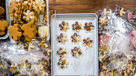 Flat lay. Carefully packaging Christmas cutout cookies, half-dipped in chocolate, sprinkled with...
