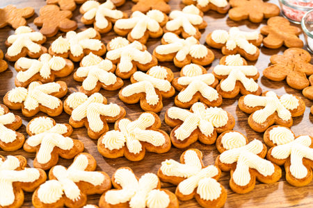 Making gingerbread man cookie sandwiches filled with eggnog buttercream, arrayed on a rustic wooden...
