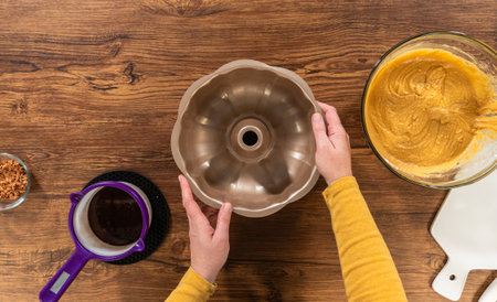 Flat lay. Carefully greasing a bundt cake pan in preparation for baking a delicious bundt cake.の写真素材