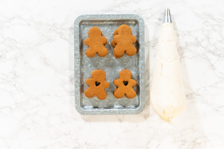 Flat lay. Gingerbread cookies await their second halves on a marble surface, each meticulously piped...
