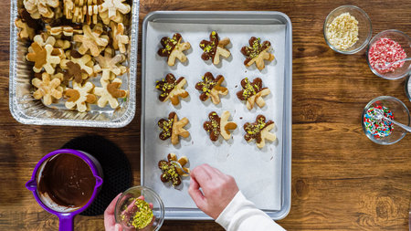 Flat lay. Creating snowflake-shaped cutout sugar cookies, dipped in chocolate, and adorned with...