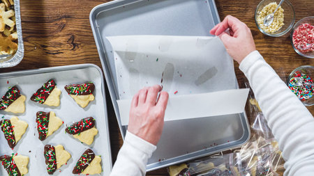 Flat lay. Carefully packaging Christmas cutout cookies, half-dipped in chocolate, sprinkled with crushed nuts, and presented in clear cellophane wrapping.の写真素材