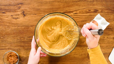 Flat lay. In a glass mixing bowl, a large hand whisk expertly blends the ingredients for a...
