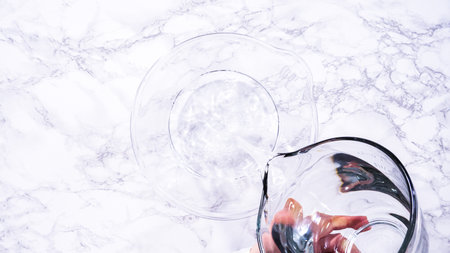 Flat lay. A spacious glass mixing bowl filled with water sits prepared to gently cleanse a batch of ripe strawberries, ensuring they are pristine before drying or storage.の写真素材