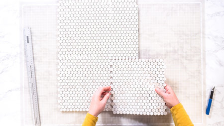 Flat lay. In the process of mounting peel and stick mosaic tiles onto a foam board, perfect for...