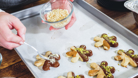 Crafting star-shaped holiday cookies dipped in chocolate and sprinkled with variety of toppings.