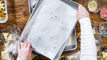 Flat lay. Carefully packaging Christmas cutout cookies, half-dipped in chocolate, sprinkled with crushed nuts, and presented in clear cellophane wrapping.の写真素材
