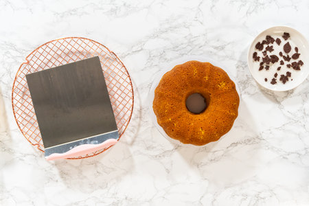 Flat lay. Icing the pumpkin bundt cake with cream cheese frosting and decorating it with chocolate leaves.の写真素材