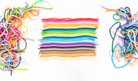 Flat lay. A vibrant collection of clay beads, neatly arranged by color on a white table, ready to...