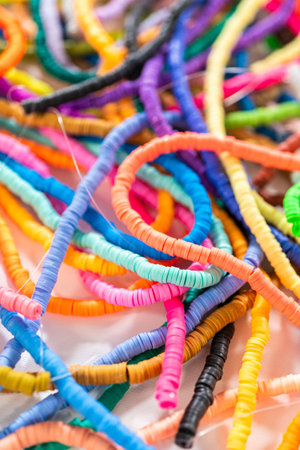 A vibrant collection of clay beads, neatly arranged by color on a white table, ready to inspire...