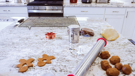 Using various festive cookie cutters, were cutting out charming gingerbread cookies from the rolled dough on the sleek marble counter, bringing holiday cheer to the modern kitchen.の写真素材