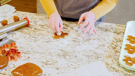 Using various festive cookie cutters, were cutting out charming gingerbread cookies from the rolled...