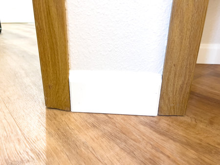 White vinyl baseboards and trim pieces are neatly stacked against a wall, prepared for installation...