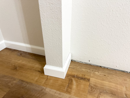 White vinyl baseboards and trim pieces are neatly stacked against a wall, prepared for installation...