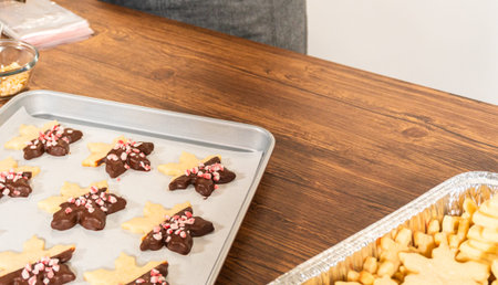 Preparing star-shaped cookies, half-dipped in chocolate, accented with peppermint chocolate chips...