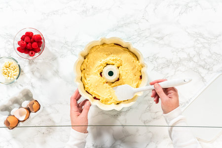 Flat lay. After greasing the bundt cake pan, its time to fill it with the prepared cake batter and delightful raspberry cake filling - creating a perfect harmony of flavors.の写真素材