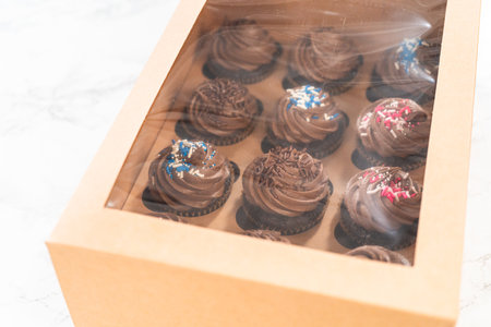 Preparing to share the delicious chocolate cupcakes, the final step involves carefully packaging them into a brown paper cupcake box.の写真素材