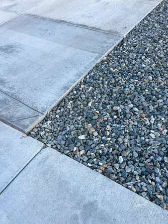 A modern concrete walkway bordered by decorative rocks, creating a clean and stylish landscaping design for outdoor spaces.の写真素材