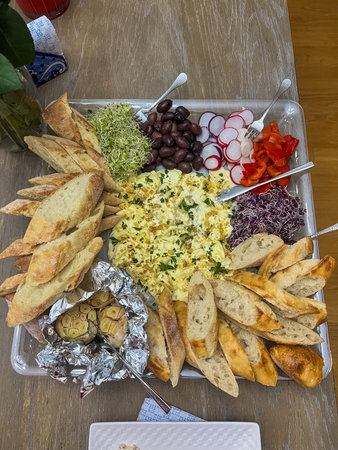 A creative butter board featuring creamy butter spread, topped with fresh herbs, roasted garlic, and...