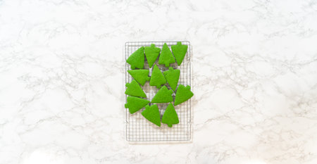 An overhead view of freshly baked green gingerbread cookies, arranged on a cooling rack over a marble surface in the Green Gingerbread Cookies recipe. The cookies are tree-shaped, showcasing a festive, vibrant green color against the neutral background.の写真素材