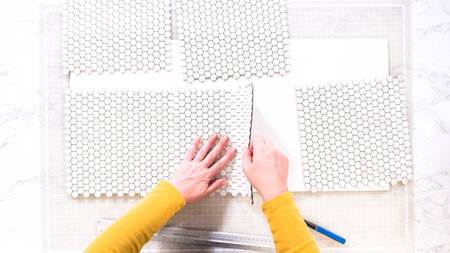 Flat lay. In the process of mounting peel and stick mosaic tiles onto a foam board, perfect for enhancing a food photography studios aesthetic.の写真素材