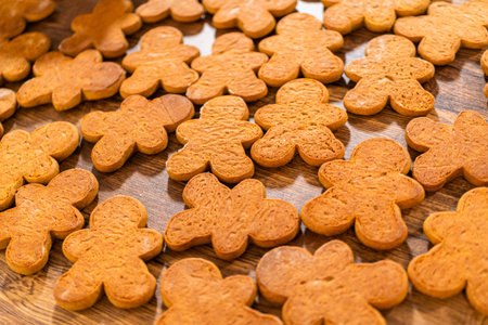 Making gingerbread man cookie sandwiches filled with eggnog buttercream, arrayed on a rustic wooden...