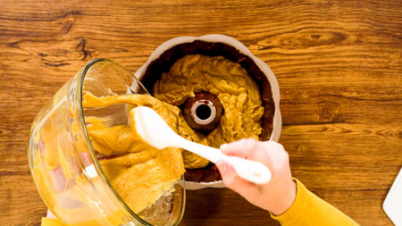 Flat lay. Pouring the gingerbread cake batter into the greased bundt cake pan, ready for a...