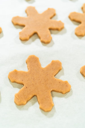 Overhead view of snowflake-shaped amber gingerbread cookie cutouts neatly arranged on a...