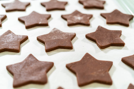 Close-up view of raw chocolate star cookies placed on parchment paper, highlighting their clean edges.の写真素材